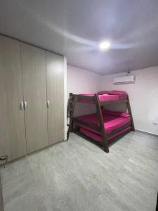 um quarto com 2 beliches e lençóis cor-de-rosa em Hostal el ebenezeer em Santa Marta