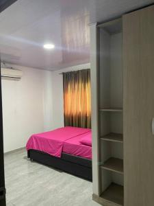 ein Schlafzimmer mit einem rosa Bett und einem Bücherregal in der Unterkunft Hostal el ebenezeer in Santa Marta