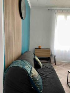 eine Couch in einem Wohnzimmer mit einer Uhr an der Wand in der Unterkunft Appartement accueillant aux portes de Paris in Bobigny