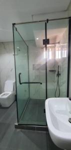 a bathroom with a glass shower and a sink at ABODE APARTMENTS in Lagos