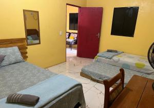 um quarto com duas camas e uma porta vermelha em Casa Amarela em Presidente Figueiredo