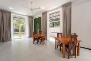 a dining room with wooden tables and chairs and windows at Villa Ceylanka in Talpe