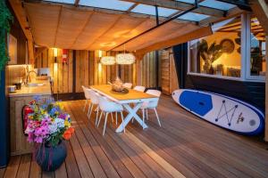 a dining room with a table and a surfboard on a deck at Cabana incl boat, jacuzzi,subboarts on a quiet park with private parking in Loosdrecht