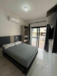 1 dormitorio con 1 cama y puerta corredera de cristal en Residencial Miragem Bombinhas, en Bombinhas