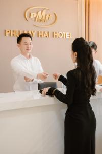 un hombre y una mujer parados en un mostrador de hotel en Phu My Hai Hotel, en Da Nang