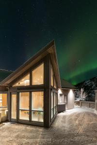 a house with the aurora in the sky at Vikran Seaside Lodge in Straumsjøen