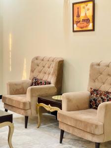 a living room with two chairs and a table at Homey Islamabad in Islamabad