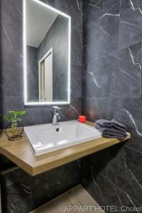 a bathroom with a sink and a mirror at Appart hotel Cholet Carteron in Cholet
