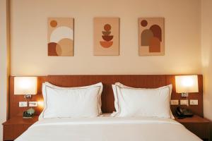 a bedroom with a bed with two pillows and two lamps at AYA Addis Hotel in Addis Ababa