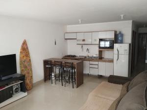 a living room with a kitchen with a refrigerator and a counter at Casa privativa no norte da ilha in Florianópolis