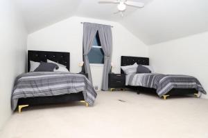 a white bedroom with two beds and a window at Charming, Central, Cozy Home - Ideal in Dearborn Heights