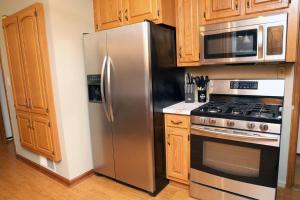 una nevera de acero inoxidable en una cocina con armarios de madera en Charming, Central, Cozy Home - Ideal, en Dearborn Heights