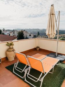 two chairs and an umbrella on a balcony at La Maysou in Masroig