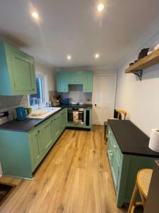 a kitchen with green cabinets and a wooden floor at Homely garden apartment, newly refurbished - sleeps four in Brighton & Hove