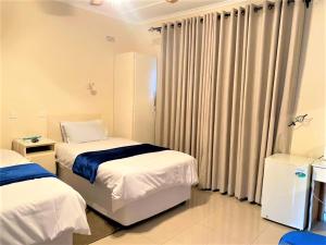 1 dormitorio con 2 camas y una ventana con cortinas en Luxurious suite with outdoor pool - 2171 en Bulawayo