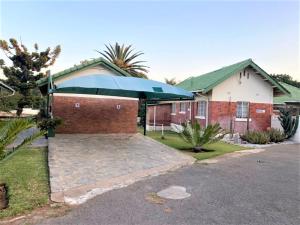 a house with a large blue umbrella in the driveway at Luxurious suite with outdoor pool - 2171 in Bulawayo