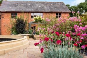 a garden with flowers in front of a brick house at Cob Barn - Great Houndbeare Farm Holiday Cottages in Aylesbeare