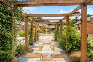 um jardim com uma pérgula de madeira e um passadiço em Cob Barn - Great Houndbeare Farm Holiday Cottages em Aylesbeare