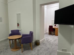 a room with a table and two chairs and a tv at Exmouth Beach Hotel in Exmouth