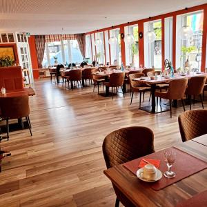 a dining room with tables and chairs and windows at Hotel Starke in Brilon