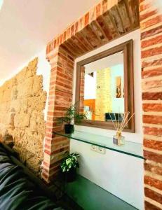 sala de estar con pared de ladrillo y espejo en La Casa Siglo Ocho, en Iznájar