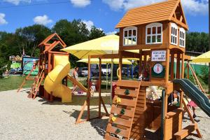 a playground with a wooden play structure and slides at Zrubový Dom 1 v Panoráma Parku in Nezbudská Lúčka