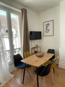 a dining room with a wooden table and chairs at Appartement hyper centre, Parking gratuit in Fontainebleau