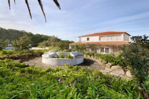 a garden with a tub in front of a house at Alto da Praia Villa in Colares