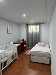 - une chambre avec un lit, un bureau et un lit bébé dans l'établissement Gouveia Family Escape, à Machico