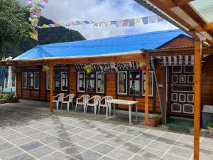 Mount kailash lodge and resturant , Monjo في Monjo: مبنى امامه كراسي وطاولة