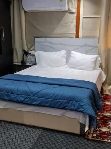 a bed with a blue blanket and white pillows at LEEHOME RESORT in Trichūr