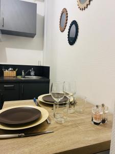 een houten tafel met wijnglazen en borden erop bij Le 2 - Grand studio avec coin repas Caen Port in Caen