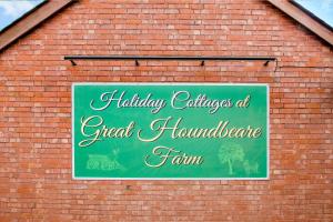 a green sign on the side of a brick building at Lime Cottage - Great Houndbeare Farm Holiday Cottages in Aylesbeare