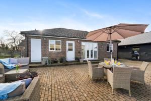 a patio with a table and chairs and an umbrella at Farm stay outside Canterbury in Stelling