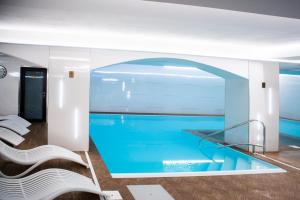 a swimming pool in the middle of a room with white chairs at Hotel Marlene in Oščadnica