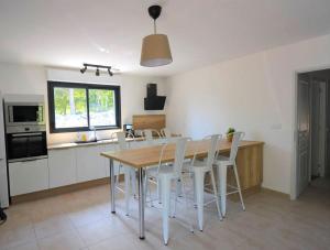 a kitchen with a wooden table and white chairs at Maison CLAPAS in Saint Alban Auriolles +2 photos