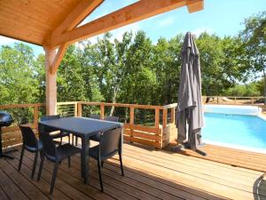 a deck with a table and an umbrella next to a swimming pool at Maison CLAPAS in Saint Alban Auriolles