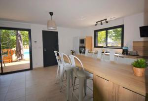 a kitchen with a large wooden bar with white chairs at Maison CLAPAS in Saint Alban Auriolles