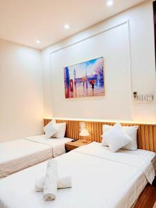two beds in a room with a painting on the wall at ELISA HOTEL in Pleiku
