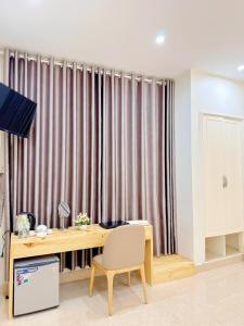 a desk and a chair in a room with curtains at ELISA HOTEL in Pleiku