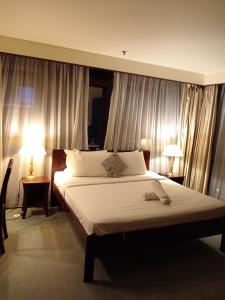 a bedroom with a large bed with white sheets and two lamps at CITY APARTMENT at TIMES SQUARE in Kuala Lumpur