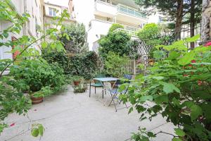 un patio con mesa, sillas y plantas en Appartement 50m2 avec terrasse idéalement situé, en Boulogne-Billancourt