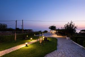 a pathway with lights on the grass at night at Barefoot Contessa in Lourdhata