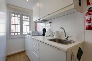 a white kitchen with a sink and a window at Home @ Porto Clérigos Apartment in Porto
