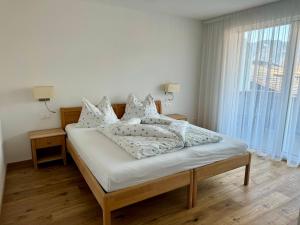 1 dormitorio con 1 cama con sábanas y almohadas blancas en Ferienwohnungen Preiss, en Scena