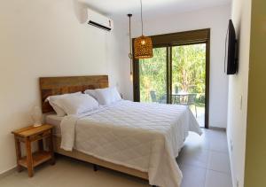 um quarto com uma cama com um edredão branco em Zaya Beach House em Ilhabela em Ilhabela