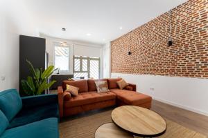a living room with a brown couch and a brick wall at Luxe Apartment Madrid North in Madrid