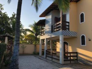 um edifício com uma varanda e uma palmeira em Casa Sol e Mar Jaconé: Um paraíso entre o mar e a lagoa em Jaconé