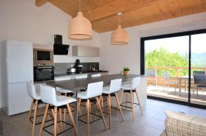 a kitchen with a table with white chairs and a counter at Mas GEORGES in Saint Alban Auriolles