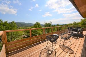 a deck with two chairs and a table on it at Mas GEORGES in Saint Alban Auriolles